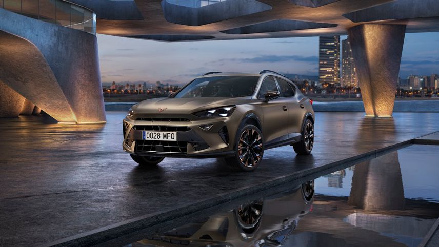 SUV CUPRA Formentor gris estacionado bajo una estructura de arquitectura moderna junto al agua al atardecer.